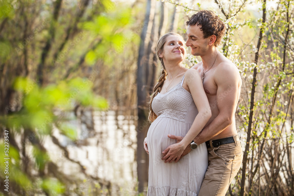 Fototapeta premium Young pregnant couple at the river in spring