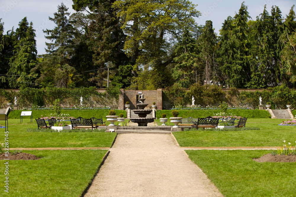 Path in a lush garden with a fountain Path in a lush garden with a fountain