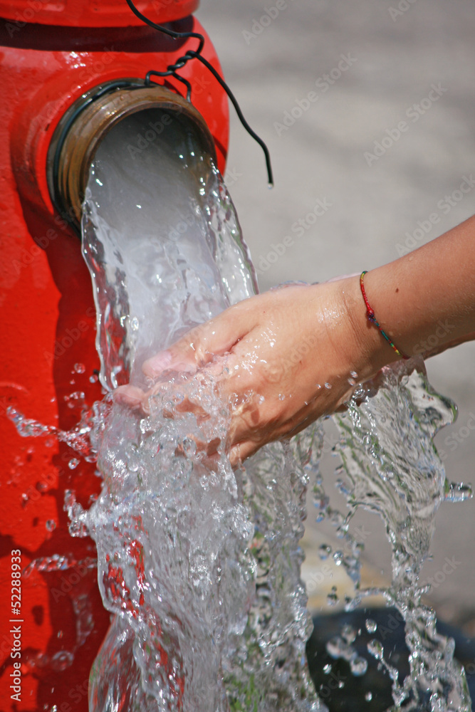 Fototapeta premium Wash hands under the powerful jet of water from a fire hydrant
