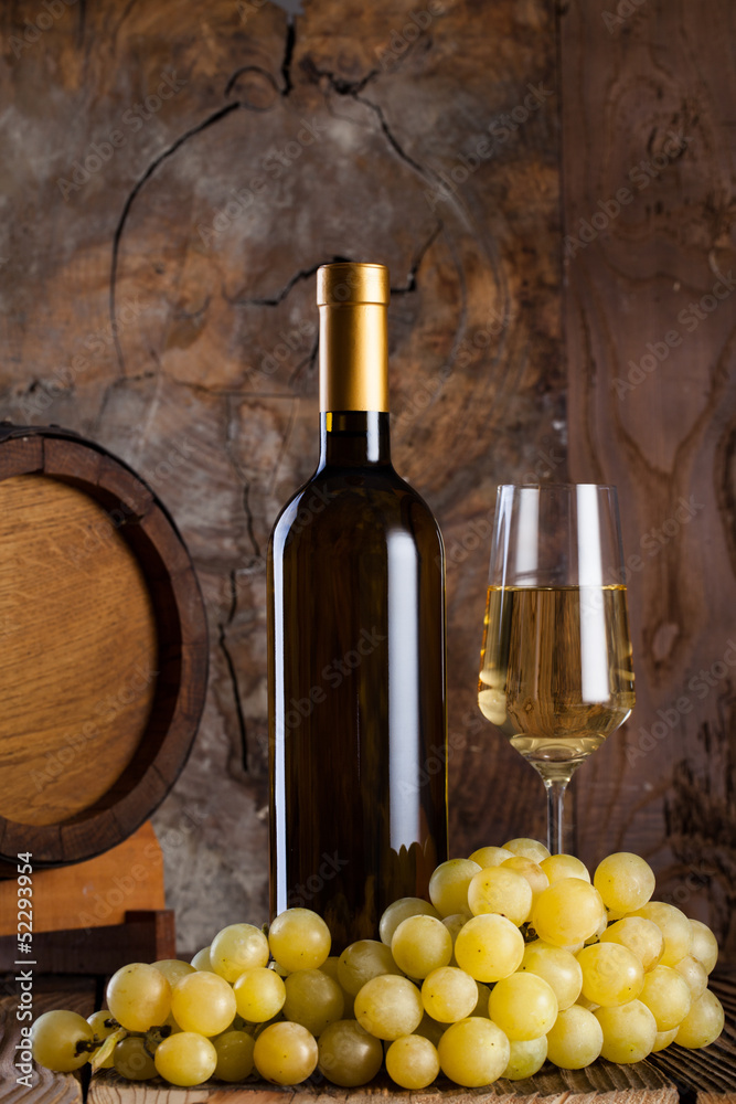 Naklejka premium White wine, grapes, old bottle and a barrel.