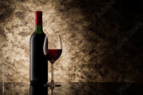 bottle with red wine and glass on a old stone