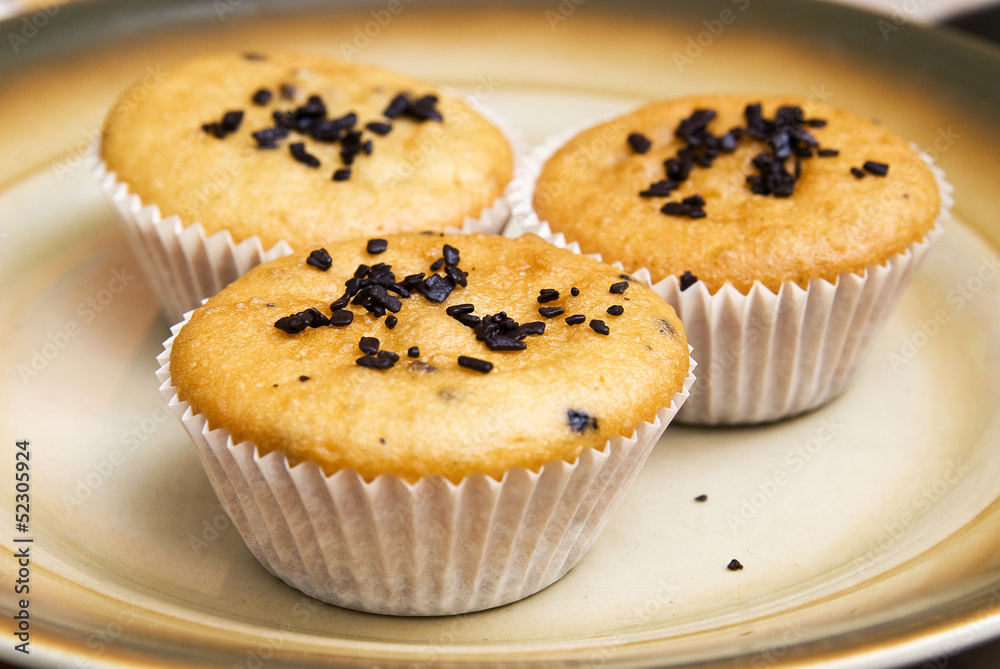 Freshly baked muffins in cups topped with chocolate . Freshly baked muffins in cups topped with chocolate .