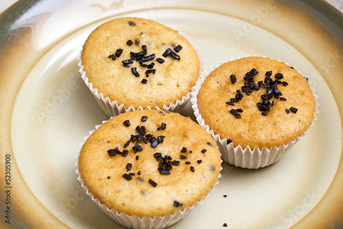 Freshly baked muffins in cups topped with chocolate .