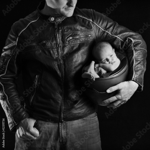 A motorcyclist father holds his newborn baby in his helmet