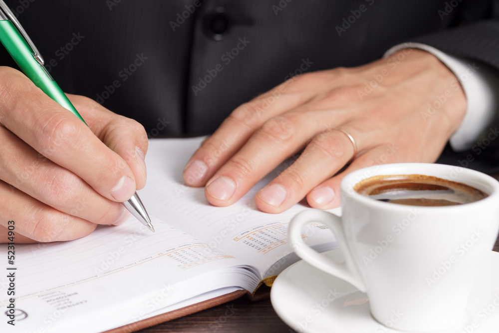Businessman notes his idea to diary Businessman notes his idea to diary