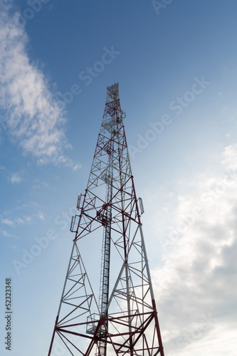 Communications tower against a blue sky with clouds.