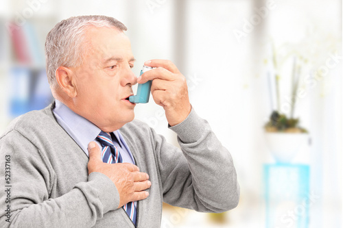 Mature man treating asthma with inhaler photo