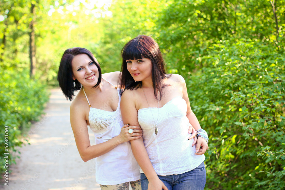 Two happy brunette women in a summer park