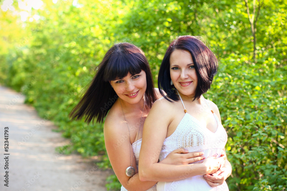 Naklejka premium Two happy brunette in a summer park
