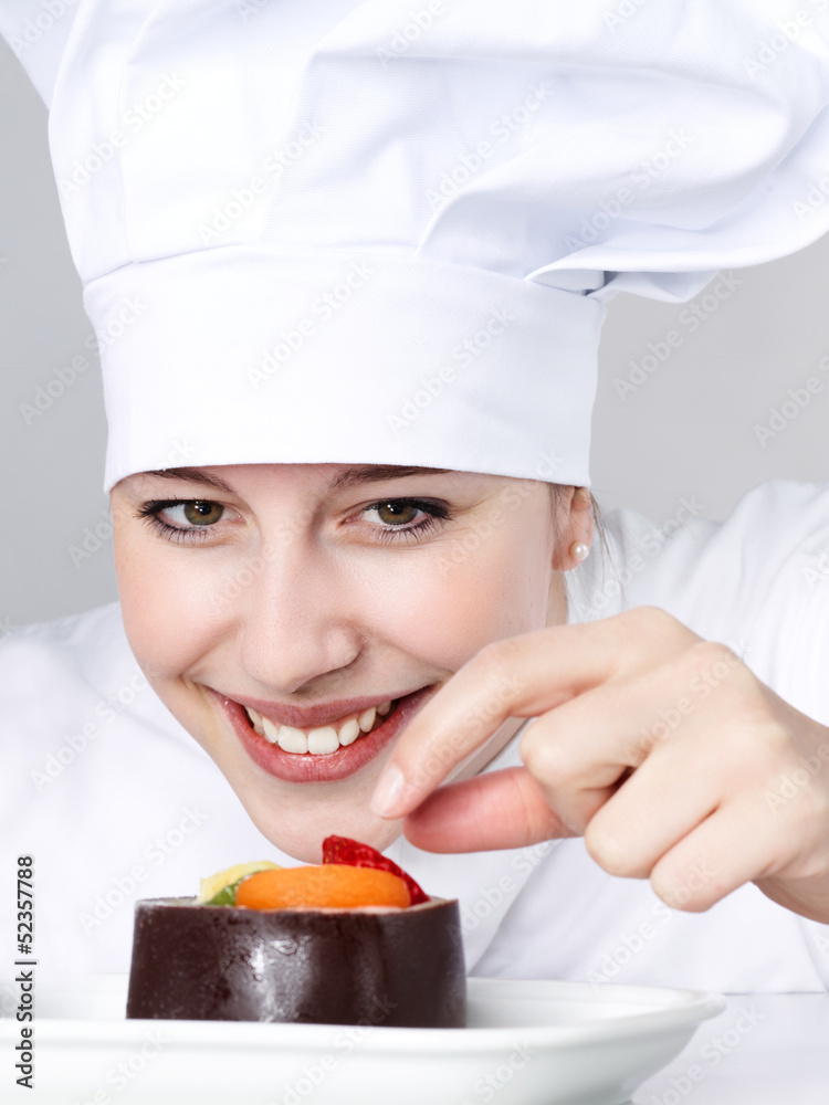 Female chef baker in uniform tasting a dessert Female chef baker in uniform tasting a dessert