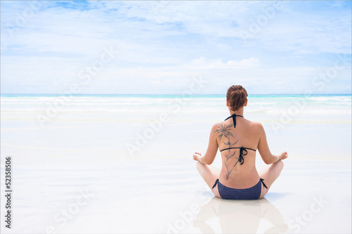 Girl meditating on beach.