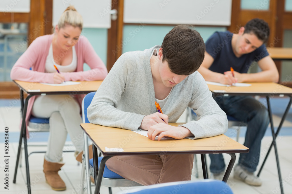 Fototapeta premium Writing students at desks in a classroom