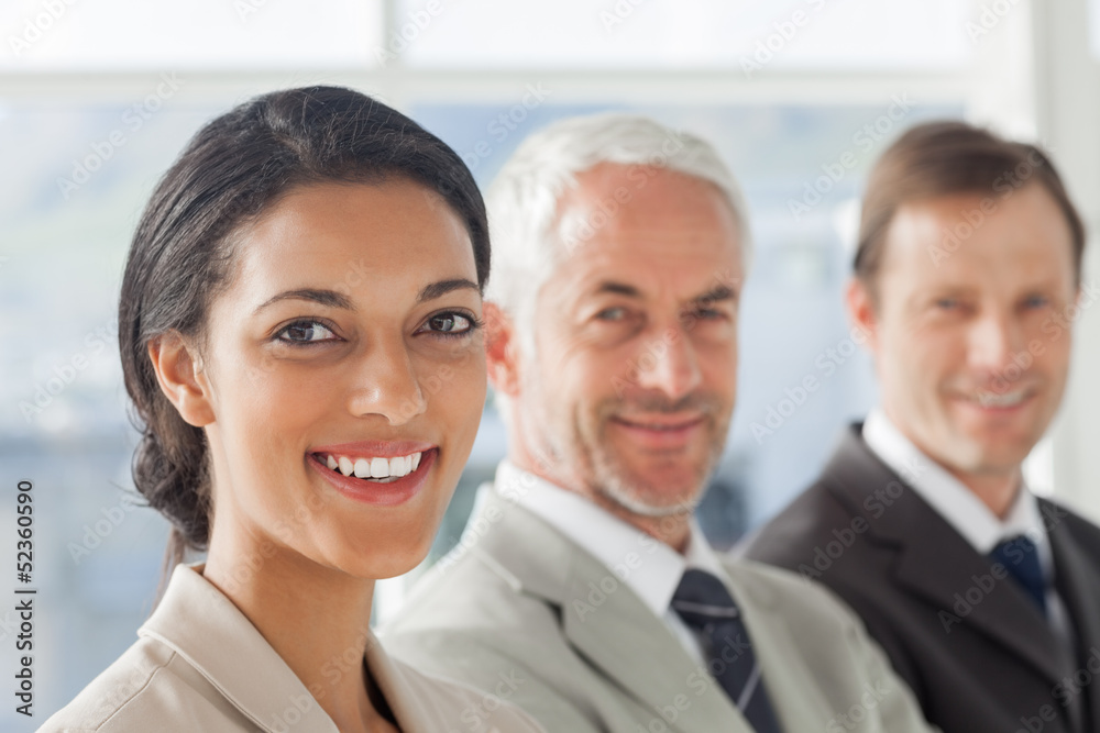 Cheerful businesswoman smiling with colleagues behind Cheerful businesswoman smiling with colleagues behind
