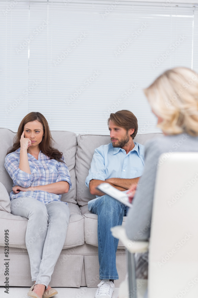 Troubled couple sit with arms folded Troubled couple sit with arms folded