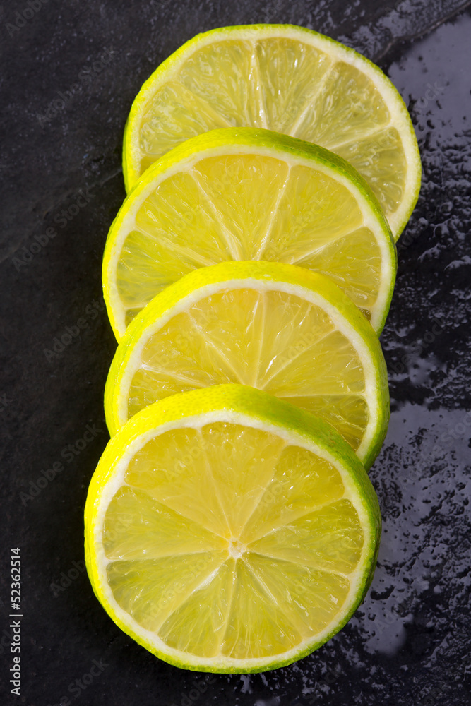 Fresh lima slices with water drops on black