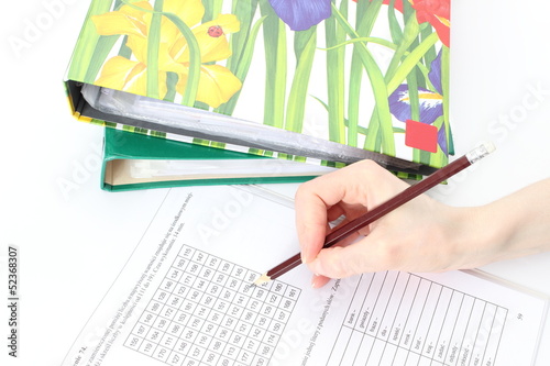 Woman's hand, pencil, documents and file folders