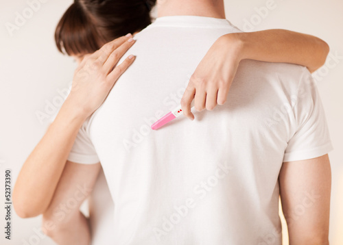 woman with pregnancy test hugging man photo