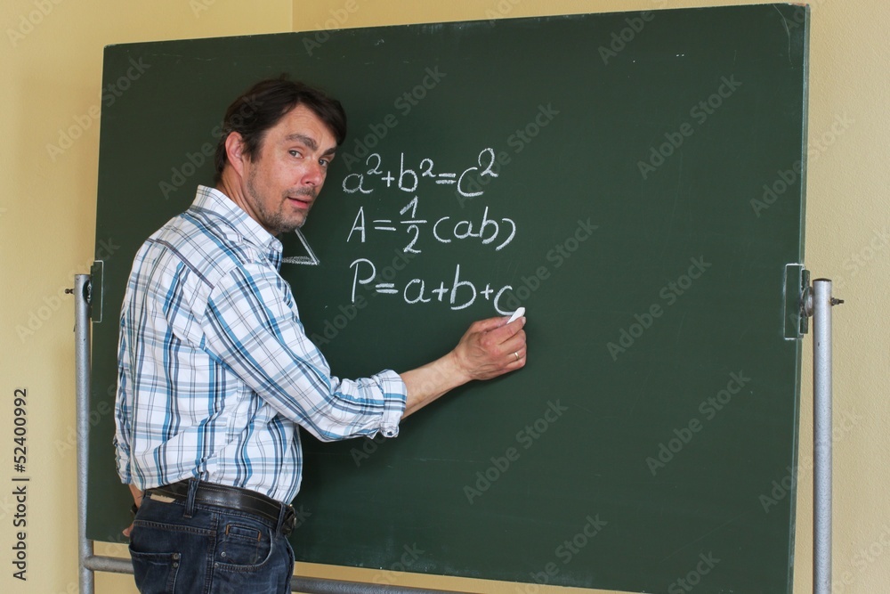 Lehrer steht an Tafel und schreibt Geometrieformel Lehrer steht an Tafel und schreibt Geometrieformel