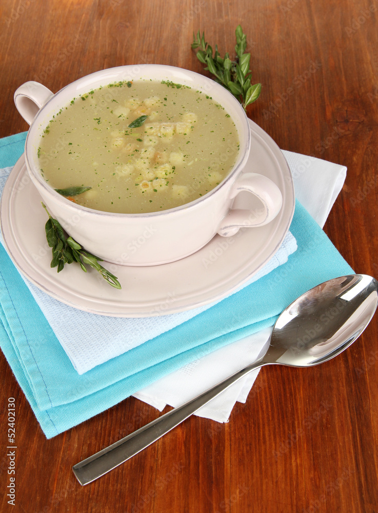 Nourishing soup in pink pan on wooden table close-up