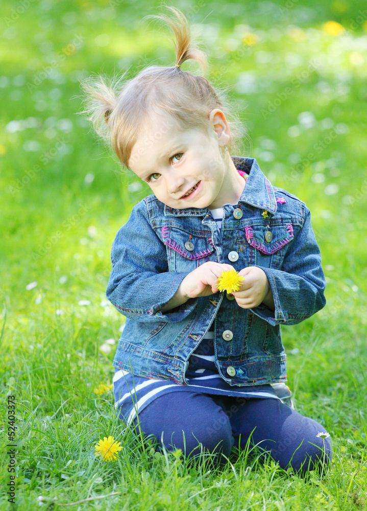 Cute girl dressed in jeans with a dandelion in a grass. Cute girl dressed in jeans with a dandelion in a grass.