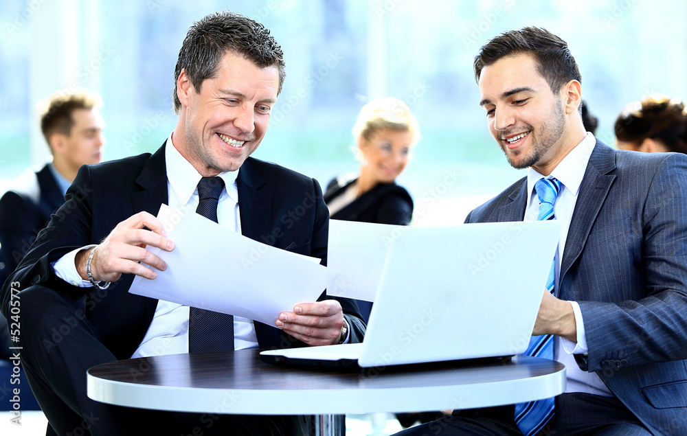 Two businessmen discussing tasks sitting at office table Two businessmen discussing tasks sitting at office table