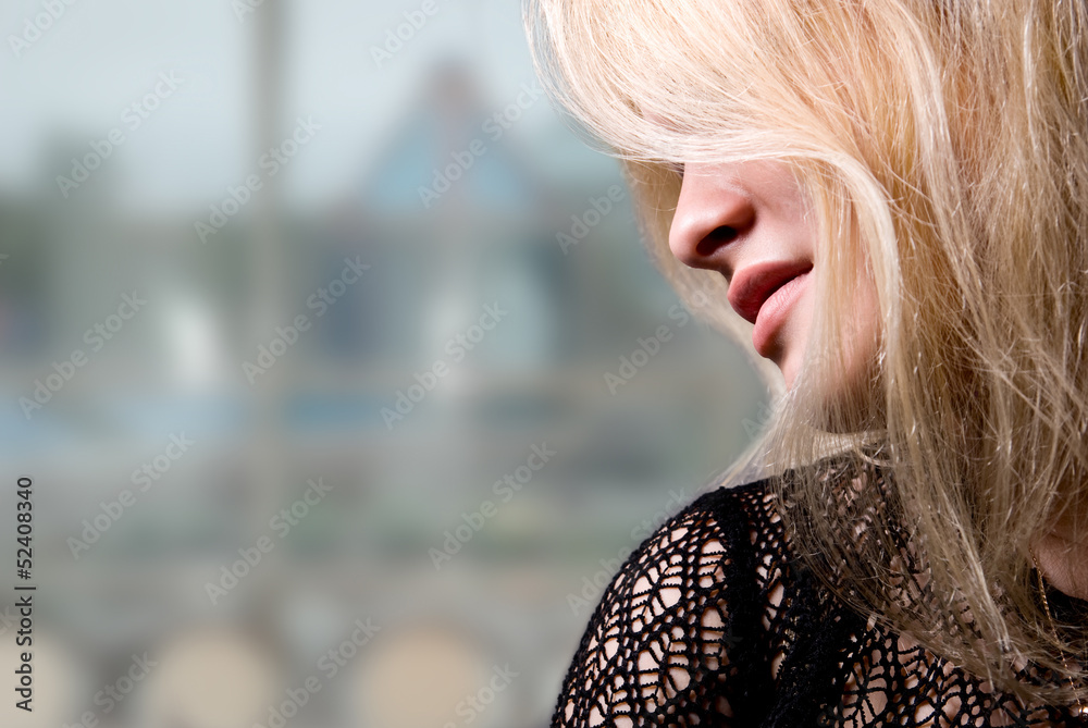 Close-up portrait of a beautiful blonde in a profile on a blurre Close-up portrait of a beautiful blonde in a profile on a blurre