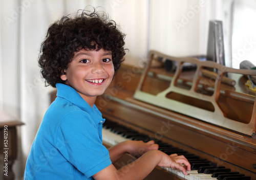 Young mixed race boy smiles while playing the piano
