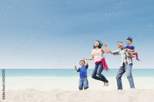 Cheerful family jumping at beach
