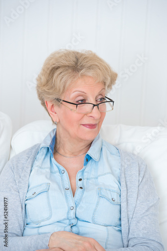 Senior woman watching tv on her sofa at home