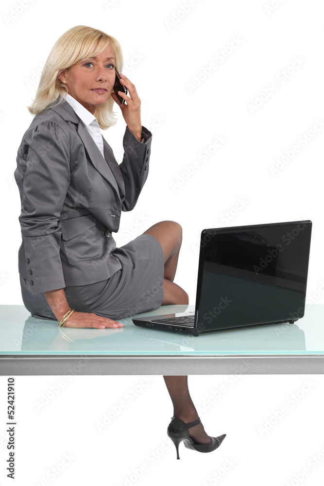 Blond executive sat on desk making call Blond executive sat on desk making call