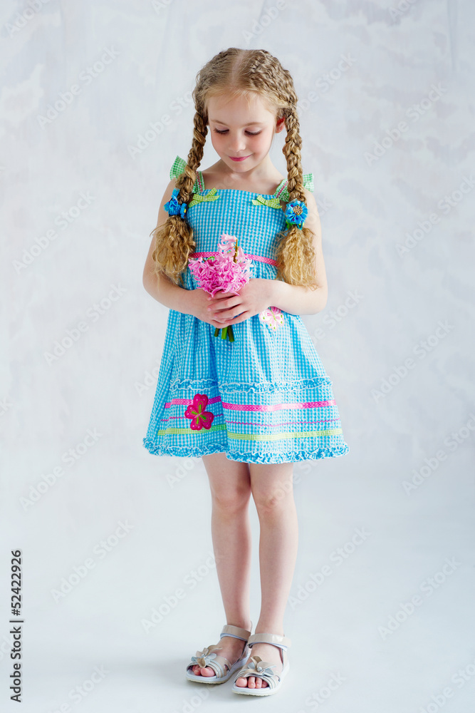Adorable girl in blue dress holding delicate pink flowers Adorable girl in blue dress holding delicate pink flowers