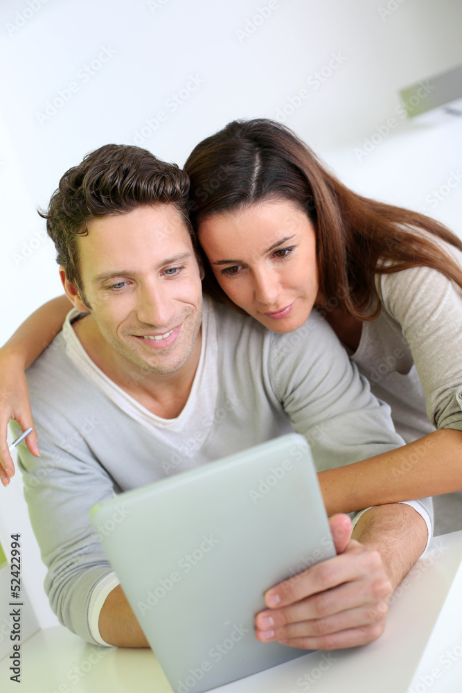 Cheerful couple websurfing on internet with tablet Cheerful couple websurfing on internet with tablet