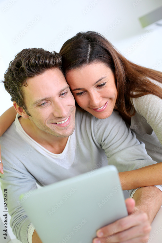 Cheerful couple websurfing on internet with tablet Cheerful couple websurfing on internet with tablet