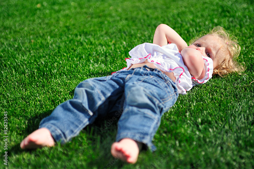 Baby girl laying on the green grass in the park Baby girl laying on the green grass in the park