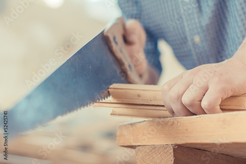 Hands handsaw sawing a board photo