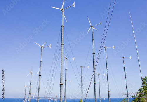 Series of wind power generators in clear blue sky background.