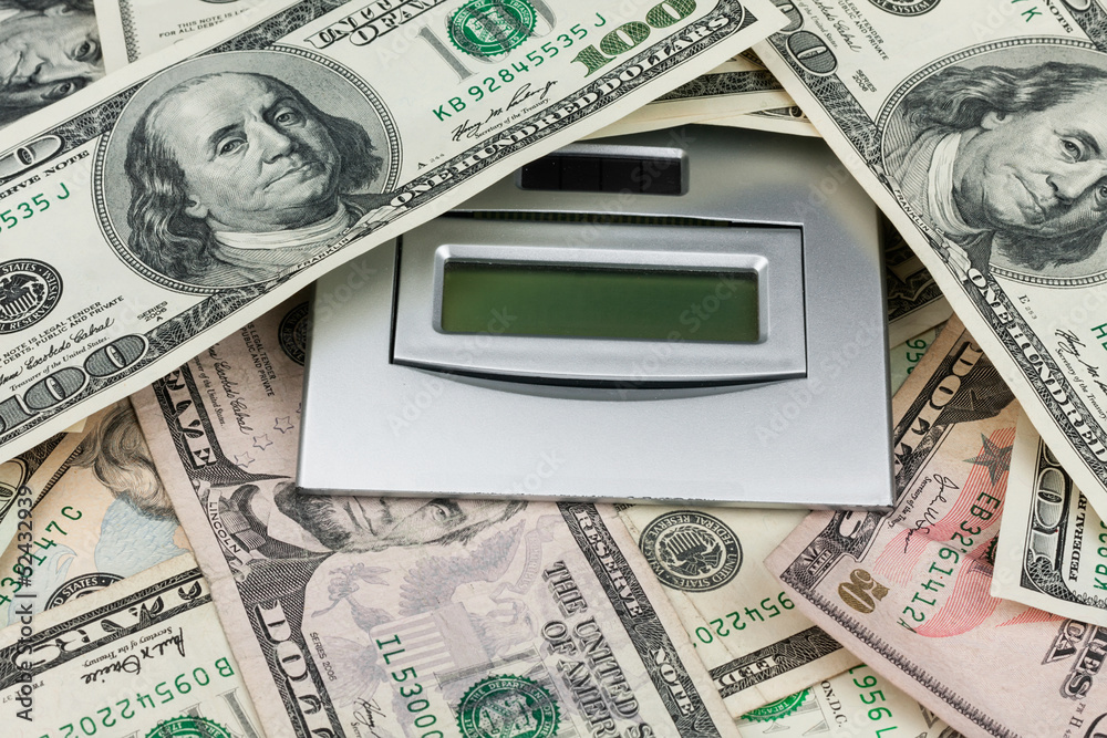 One hundred dollar  lying on the calculator