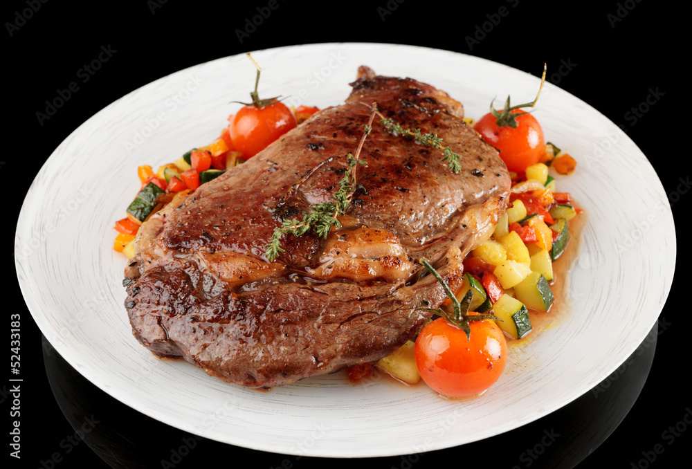 Ribeye steak with stir fried vegetables isolated on black