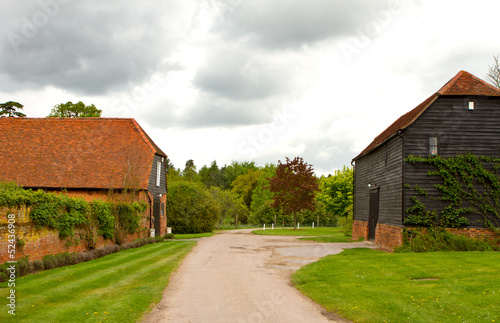 Farm and outbuildings in an English countryside scene on a storm