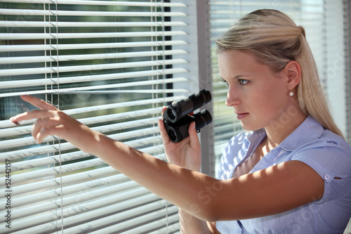 Fotografia woman looking through the blinds with binoculars