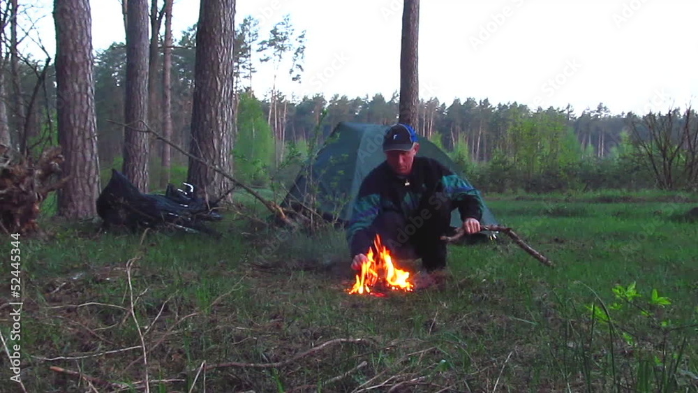 man tourist is heated near a fire in wood man tourist is heated near a fire in wood