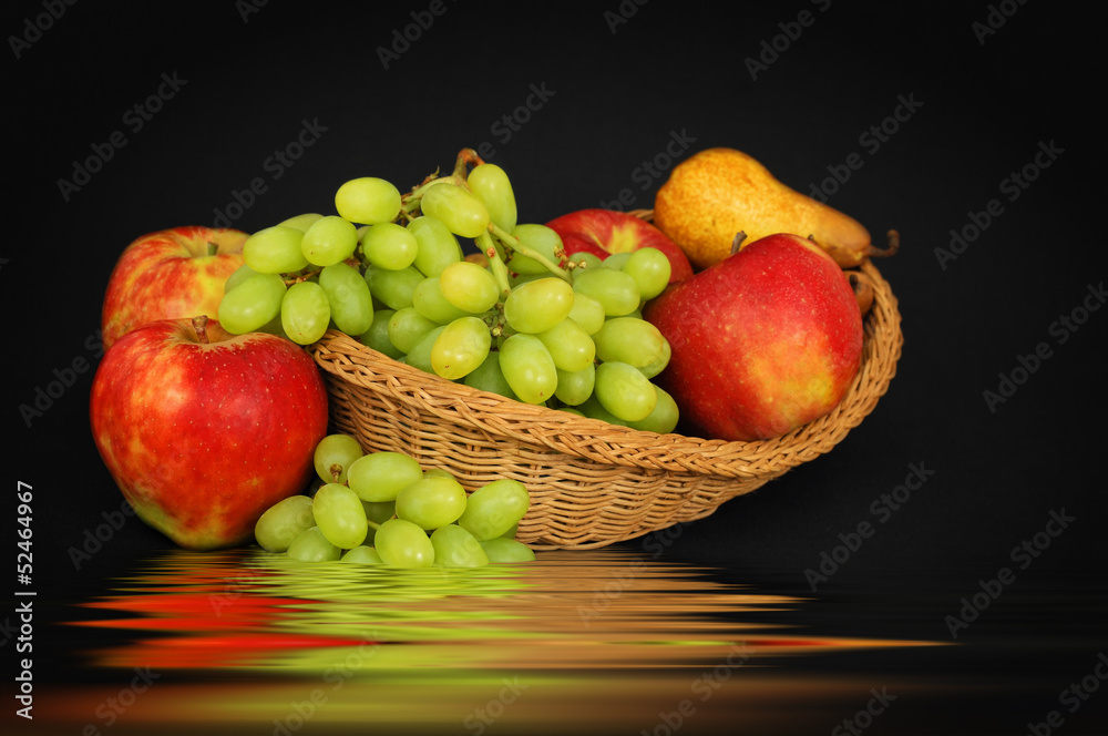 Basket with fruits above water on dark background Basket with fruits above water on dark background