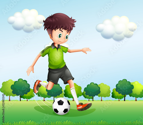 A boy with a green t-shirt playing football