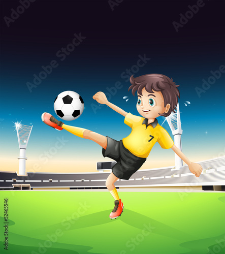A boy in a yellow uniform playing soccer in the soccer field