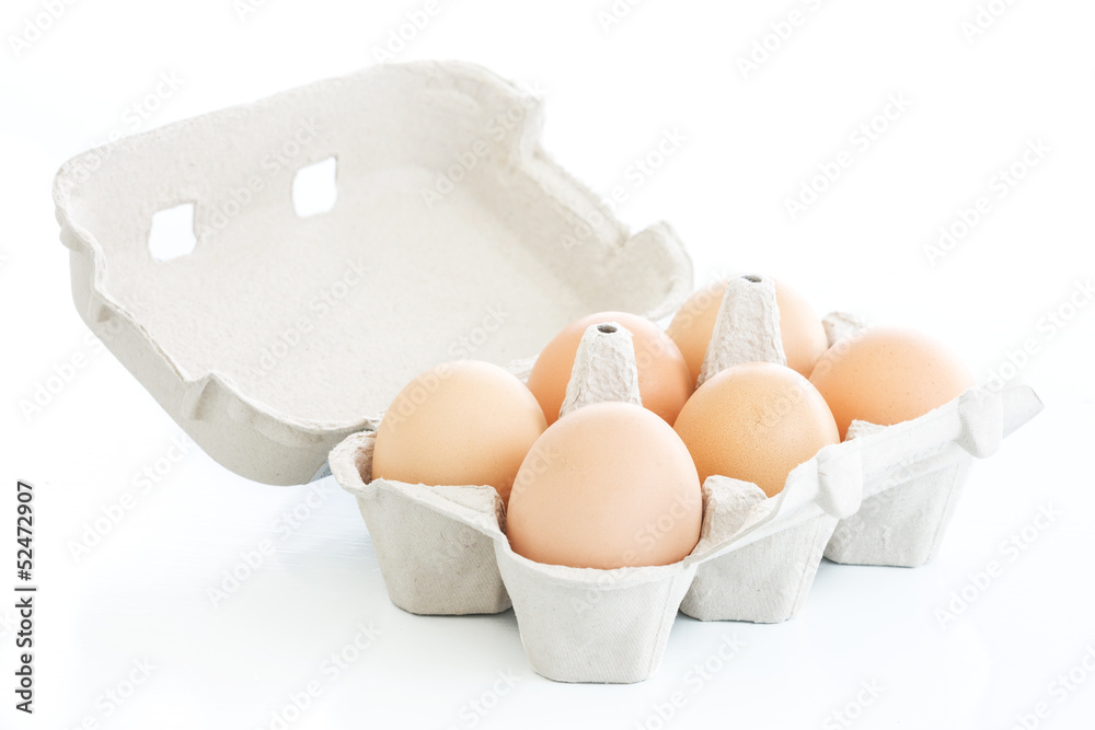 Six eggs on a carton box over white