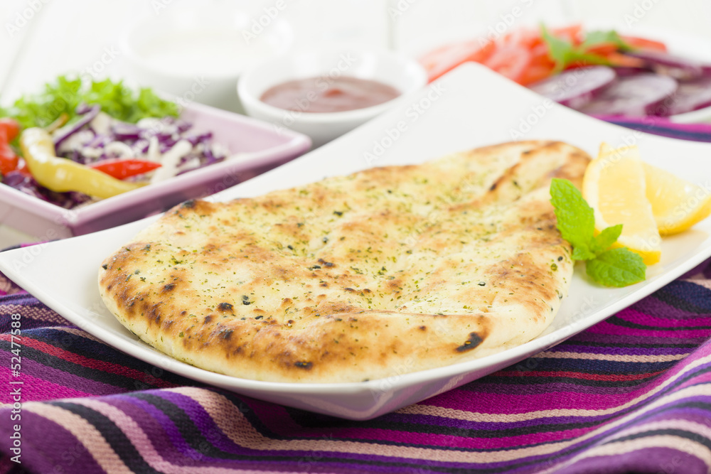 Garlic and coriander naan with lemon wedges and salad Garlic and coriander naan with lemon wedges and salad