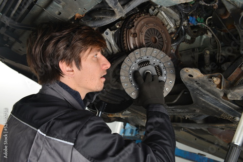 Auto mechanic working under the car and changing clutch