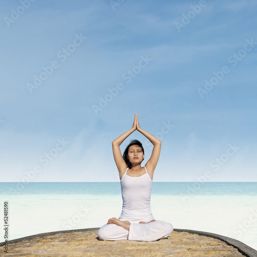 Asian woman practicing yoga at beach