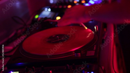 DJ scratching vinyl record plate in nightclub