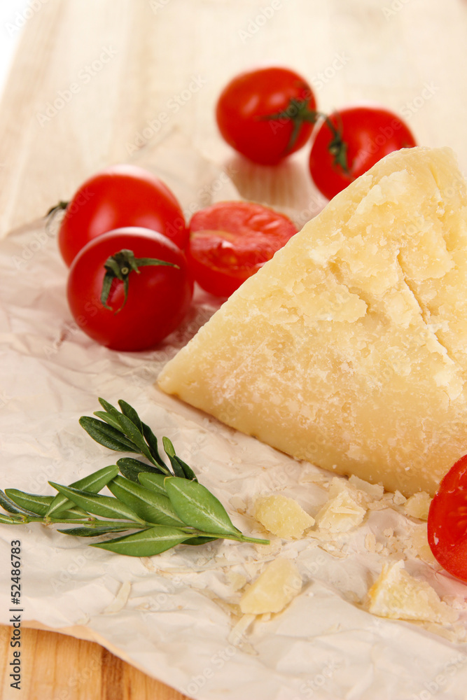 Piece of Parmesan cheese on paper on wooden table close-up Piece of Parmesan cheese on paper on wooden table close-up